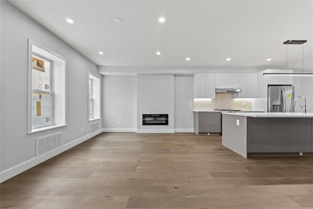 2118 45th Ave Unit 1And 2, Long Island City, NY 11101 - kitchen with stainless steel fridge, modern cabinets, under cabinet range hood, white cabinets, and light countertops
