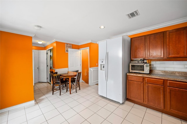 924 Otsego Ct, West Hempstead, NY 11552 - kitchen featuring white refrigerator with ice dispenser, crown molding, light tile patterned floors, and dark countertops