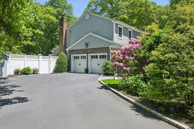 1 Highwoods Rd, Saint James, NY 11780 - view of home's exterior featuring a chimney, stone siding, asphalt driveway, and a garage