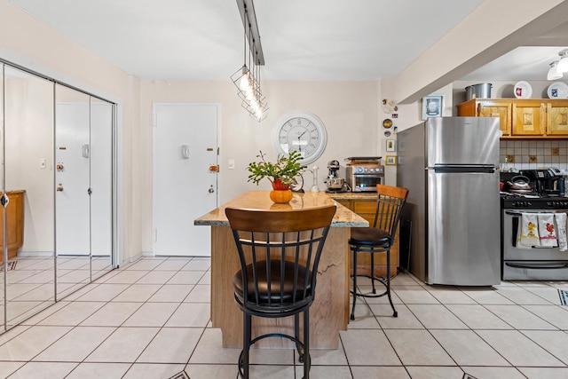 68-20 Selfridge St Unit 2F, Forest Hills, NY 11375 - kitchen featuring appliances with stainless steel finishes, light tile patterned floors, decorative backsplash, a center island, and a kitchen breakfast bar