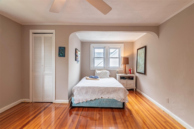 103 Fairfield Ave, Mineola, NY 11501 - bedroom featuring arched walkways, light wood finished floors, a closet, baseboards, and crown molding