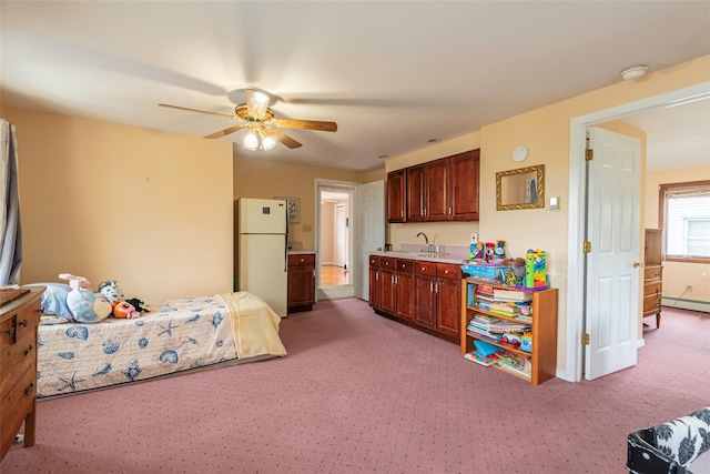 103 Fairfield Ave, Mineola, NY 11501 - bedroom featuring freestanding refrigerator, a baseboard heating unit, a sink, light colored carpet, and ceiling fan