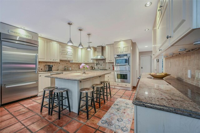 51 Eagle Chase, Woodbury, NY 11797 - kitchen with appliances with stainless steel finishes, tasteful backsplash, wall chimney exhaust hood, a breakfast bar, and a center island
