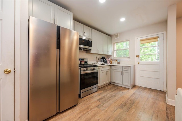 3739 Barnes Ave, Bronx, NY 10467 - kitchen with appliances with stainless steel finishes, light wood-style flooring, light countertops, white cabinets, and recessed lighting