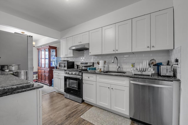 23-19 93rd St, East Elmhurst, NY 11369 - kitchen with appliances with stainless steel finishes, a sink, under cabinet range hood, backsplash, and white cabinets