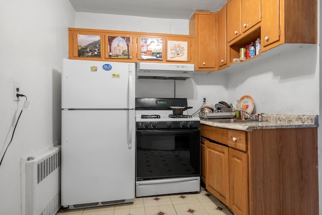 23-19 93rd St, East Elmhurst, NY 11369 - kitchen with freestanding refrigerator, under cabinet range hood, gas stove, radiator heating unit, and brown cabinetry