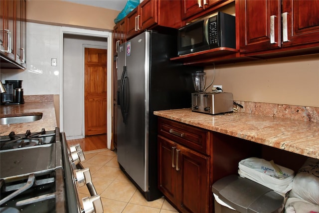 83-37 Saint James Ave Unit 2R, Elmhurst, NY 11373 - kitchen featuring reddish brown cabinets, stainless steel appliances, light tile patterned flooring, light stone countertops, and a sink
