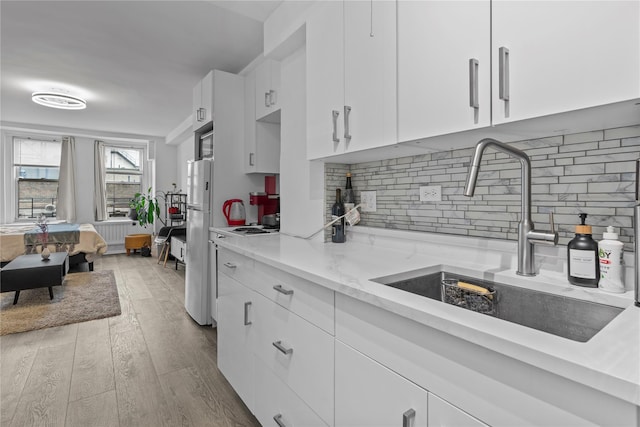 310 Riverside Dr Unit 1509, New York Manhattan, NY 10025 - kitchen with white cabinets, wood finished floors, light stone countertops, tasteful backsplash, and freestanding refrigerator