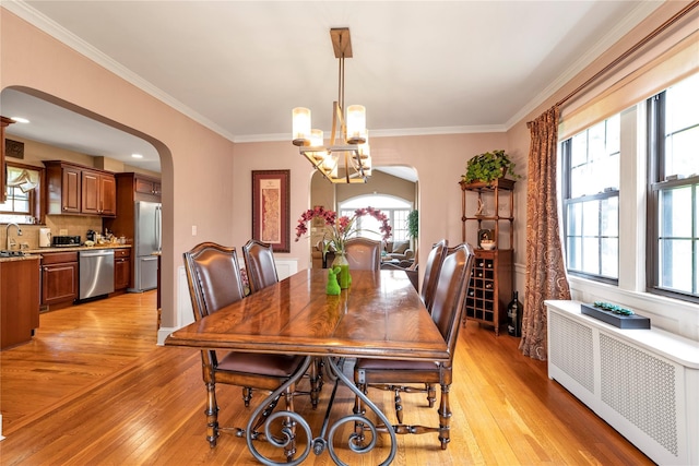 45 Henry St, Merrick, NY 11566 - dining room with radiator, arched walkways, light wood-style floors, plenty of natural light, and ornamental molding