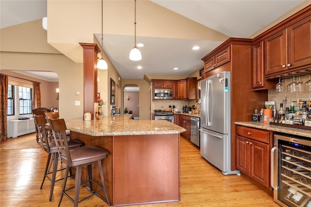 45 Henry St, Merrick, NY 11566 - kitchen featuring wine cooler, stainless steel appliances, arched walkways, light wood-style floors, and radiator heating unit