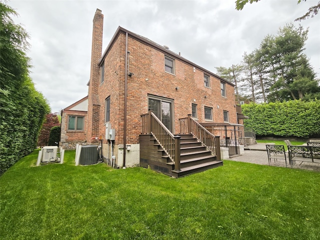 352 Mill Spring Rd, Manhasset, NY 11030 - rear view of house with central AC, a chimney, brick siding, and a lawn