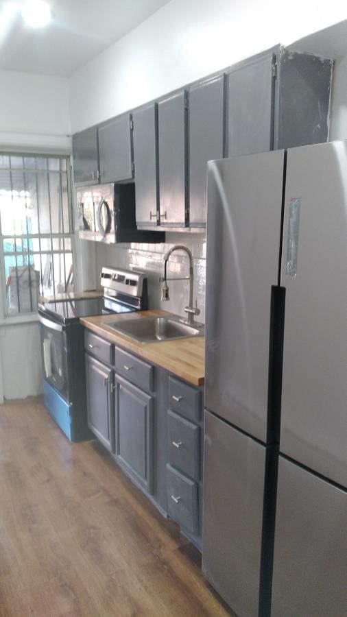 3317 87th St, Jackson Heights, NY 11372 - kitchen featuring appliances with stainless steel finishes, gray cabinets, a sink, wood finished floors, and tasteful backsplash
