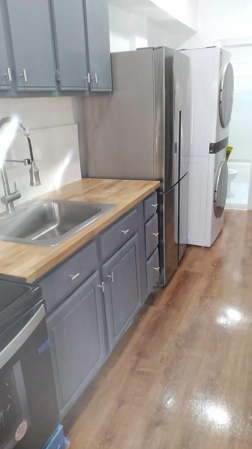 3317 87th St, Jackson Heights, NY 11372 - kitchen with stacked washer and clothes dryer, a sink, butcher block countertops, and light wood-style flooring