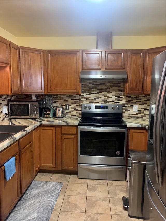 304 Warburton Ave Unit 3A, Yonkers, NY 10701 - kitchen with appliances with stainless steel finishes, under cabinet range hood, tasteful backsplash, and brown cabinetry