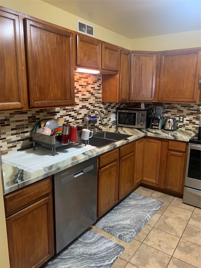 304 Warburton Ave Unit 3A, Yonkers, NY 10701 - kitchen featuring stainless steel appliances, backsplash, a sink, light tile patterned flooring, and brown cabinets
