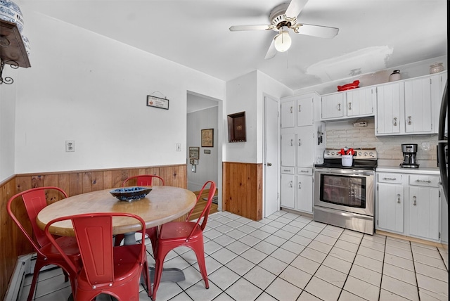 57 Panorama Dr, Patterson, NY 12563 - kitchen featuring stainless steel range with electric stovetop, wainscoting, wood walls, a ceiling fan, and light countertops