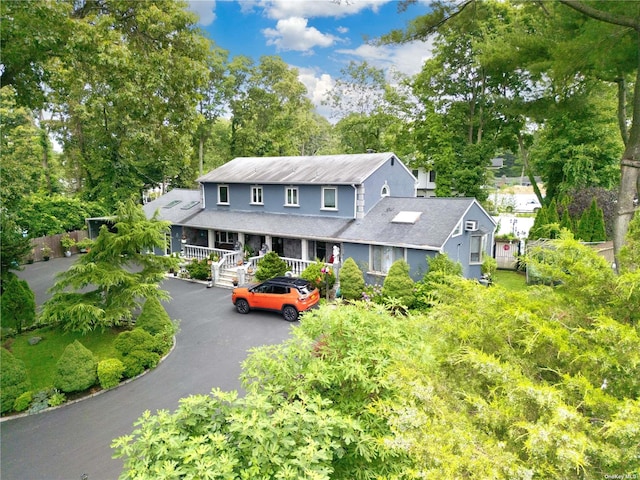 338 Cold Spring Rd, Syosset, NY 11791 - view of front of home with a porch, a shingled roof, asphalt driveway, and view of wooded area