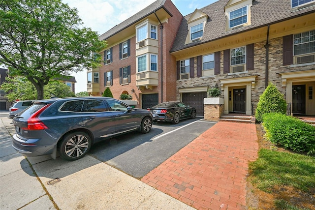 206-05 Emily Rd Unit 6U, Bayside, NY 11360 - view of front of house featuring driveway, roof with shingles, brick siding, and a garage