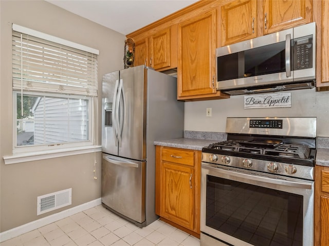 47 Muirfield Ct, Poughkeepsie, NY 12603 - kitchen with appliances with stainless steel finishes, brown cabinets, light tile patterned flooring, and light countertops