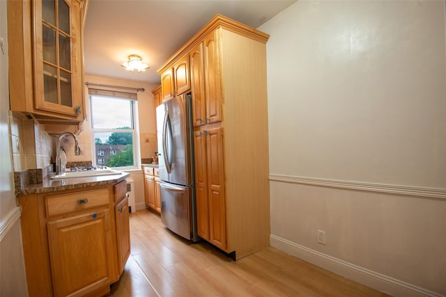 1 Georgia Ave Unit 5A, Bronxville, NY 10708 - kitchen with freestanding refrigerator, light wood finished floors, glass insert cabinets, a sink, and decorative backsplash