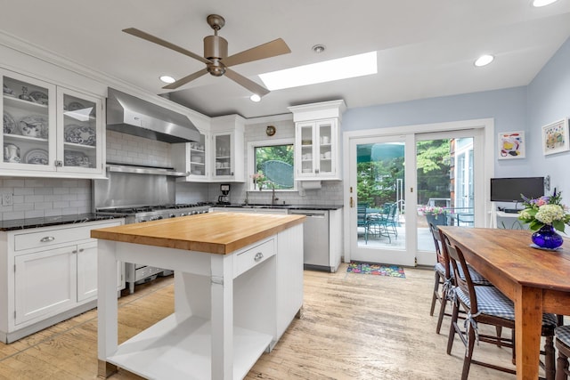 301 Margaret Blvd, Merrick, NY 11566 - kitchen featuring wooden counters, stainless steel dishwasher, wall chimney exhaust hood, stove, and white cabinetry