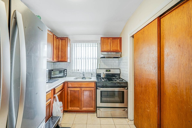 14015 159th St, Jamaica, NY 11434 - kitchen featuring stainless steel appliances, a sink, under cabinet range hood, light tile patterned floors, and tasteful backsplash