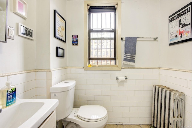 230 S 2nd St, Brooklyn, NY 11211 - half bath featuring radiator heating unit, tile walls, toilet, a wainscoted wall, and vanity