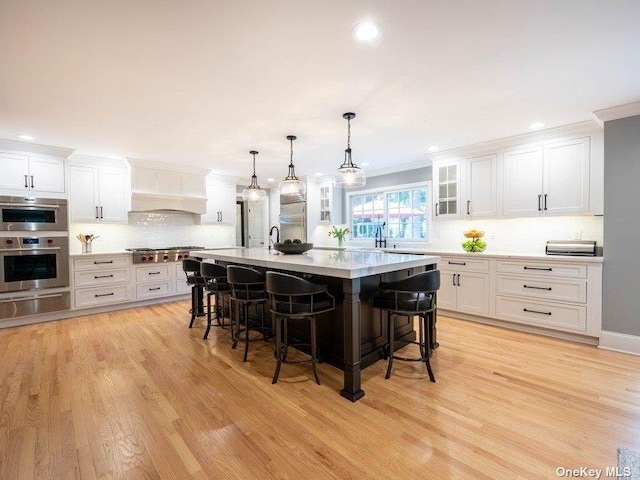 22 Homer Pl, Manhasset, NY 11030 - kitchen with a warming drawer, a breakfast bar, crown molding, white cabinetry, and light countertops