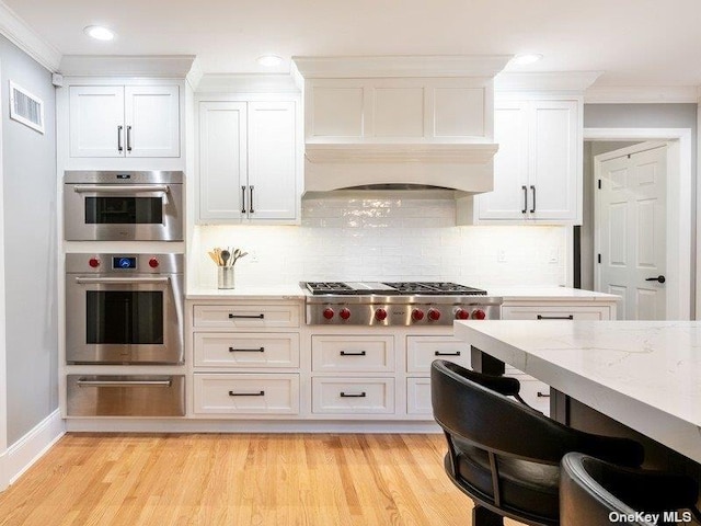 22 Homer Pl, Manhasset, NY 11030 - kitchen featuring a warming drawer, appliances with stainless steel finishes, ornamental molding, white cabinets, and decorative backsplash