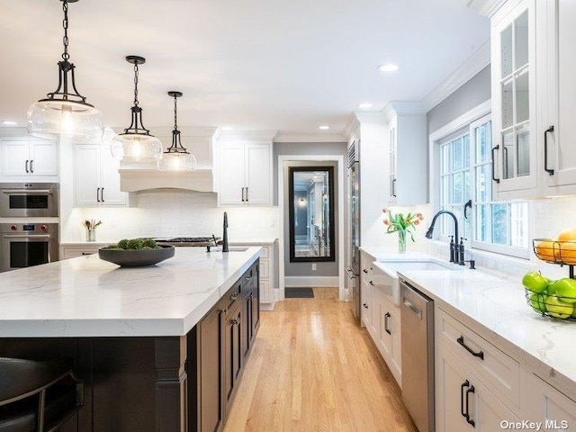 22 Homer Pl, Manhasset, NY 11030 - kitchen with appliances with stainless steel finishes, white cabinets, decorative backsplash, light stone counters, and a sink