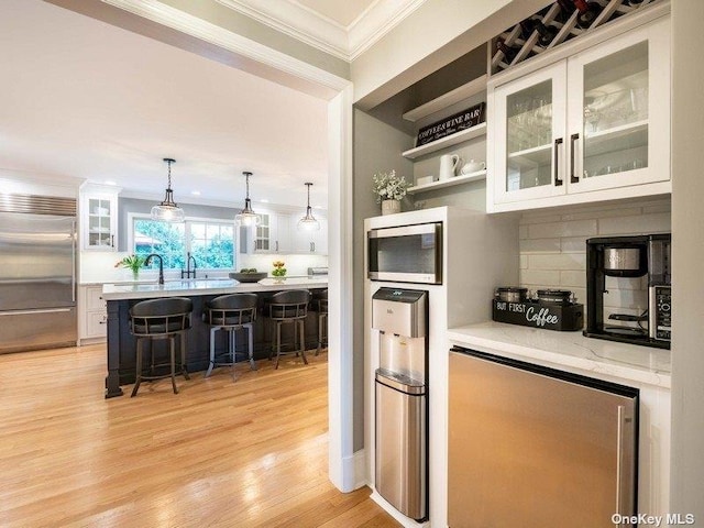 22 Homer Pl, Manhasset, NY 11030 - kitchen featuring stainless steel appliances, ornamental molding, a kitchen breakfast bar, white cabinets, and backsplash