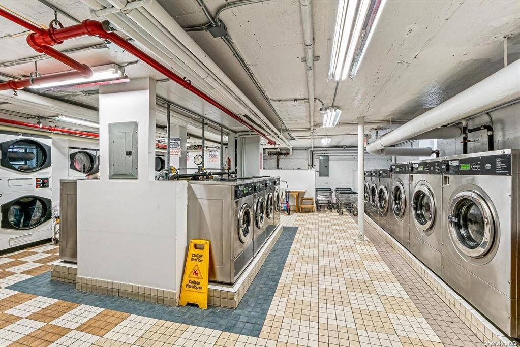 89-10 35th Ave Unit E-7R, Jackson Heights, NY 11372 - community laundry room with estacked washer and dryer, washer and dryer, electric panel, and tile patterned floors