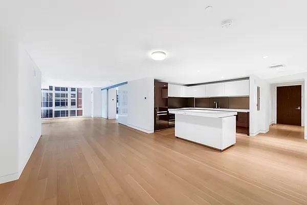 135 W 52nd St Unit 8D, New York Manhattan, NY 10019 - kitchen featuring a kitchen island, light wood finished floors, white cabinets, light countertops, and open floor plan