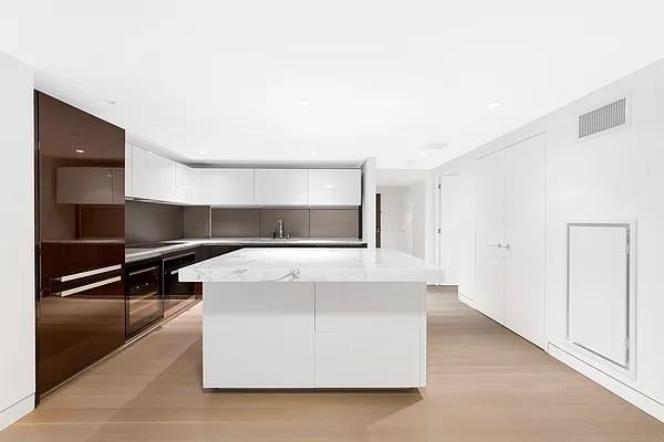 135 W 52nd St Unit 8D, New York Manhattan, NY 10019 - kitchen with modern cabinets, white cabinetry, a kitchen island, light countertops, and light wood finished floors
