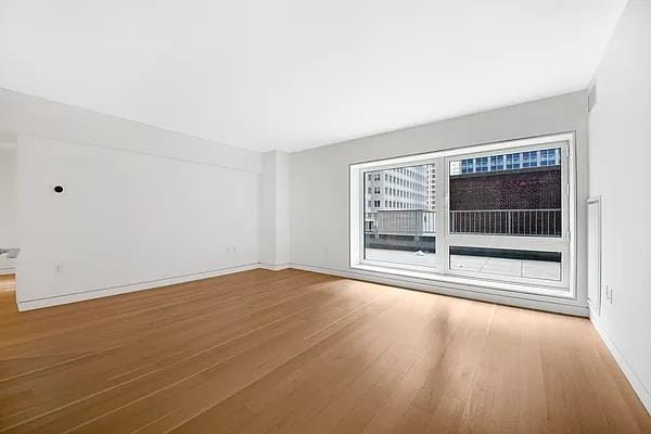 135 W 52nd St Unit 8D, New York Manhattan, NY 10019 - empty room with wood finished floors and baseboards