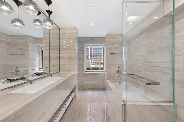 135 W 52nd St Unit 8D, New York Manhattan, NY 10019 - bathroom featuring a bath, tile walls, an enclosed shower, and a sink
