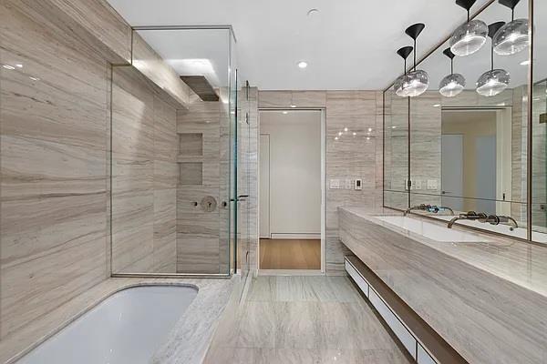 135 W 52nd St Unit 8D, New York Manhattan, NY 10019 - bathroom featuring an enclosed shower, a bathtub, vanity, a baseboard radiator, and marble finish flooring