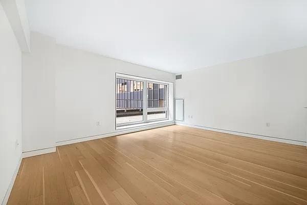 135 W 52nd St Unit 8D, New York Manhattan, NY 10019 - spare room with wood finished floors and baseboards
