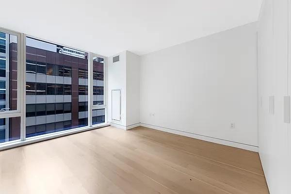 135 W 52nd St Unit 8D, New York Manhattan, NY 10019 - spare room with wood finished floors and baseboards