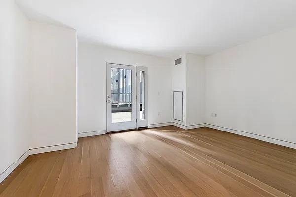 135 W 52nd St Unit 8D, New York Manhattan, NY 10019 - spare room with wood finished floors and baseboards