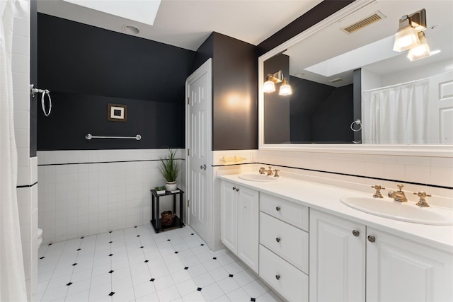 19 Rock Hill Ln, Scarsdale, NY 10583 - bathroom with a skylight, double vanity, toilet, a wainscoted wall, and tile walls