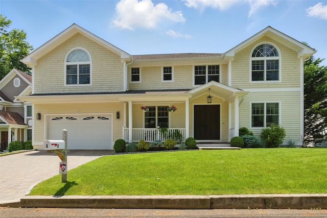 9 Constance Ave, Dobbs Ferry, NY 10522 - view of front facade with covered porch, driveway, a front yard, and an attached garage