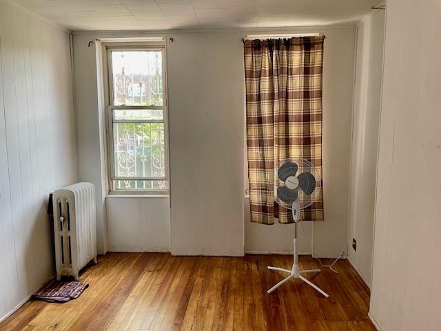 32-17 46th St, Astoria, NY 11103 - spare room featuring radiator and wood-type flooring