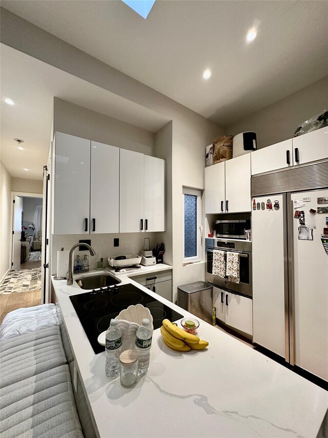 2564 38th St, Astoria, NY 11103 - kitchen with stainless steel appliances, a sink, recessed lighting, white cabinets, and tasteful backsplash