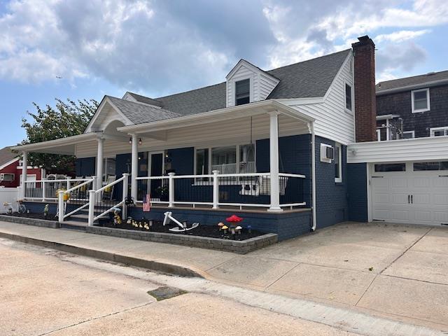 27 Armour St, Long Beach, NY 11561 - view of front of house with covered porch, an attached garage, driveway, and a shingled roof