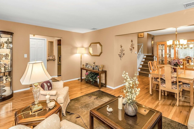 1197 Tulip Ave, Franklin Square, NY 11010 - living room featuring light wood-style floors, a chandelier, stairway, and baseboards