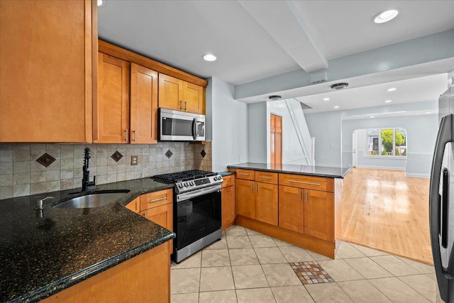11148 128th St, South Ozone Park, NY 11420 - kitchen featuring stainless steel appliances, a sink, a peninsula, backsplash, and brown cabinets
