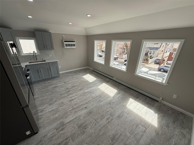 10917 124th St, South Ozone Park, NY 11420 - unfurnished dining area featuring baseboard heating, a sink, light wood-type flooring, an AC wall unit, and baseboards