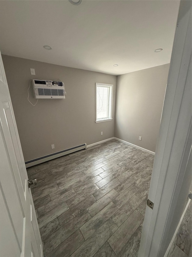 10917 124th St, South Ozone Park, NY 11420 - empty room featuring a baseboard radiator, a wall mounted air conditioner, wood finished floors, and baseboards