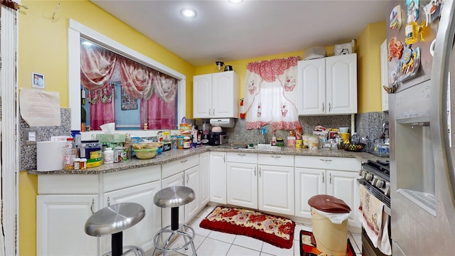 10920 116th St, South Ozone Park, NY 11420 - kitchen with stainless steel range with gas stovetop, a sink, white cabinets, light tile patterned floors, and recessed lighting